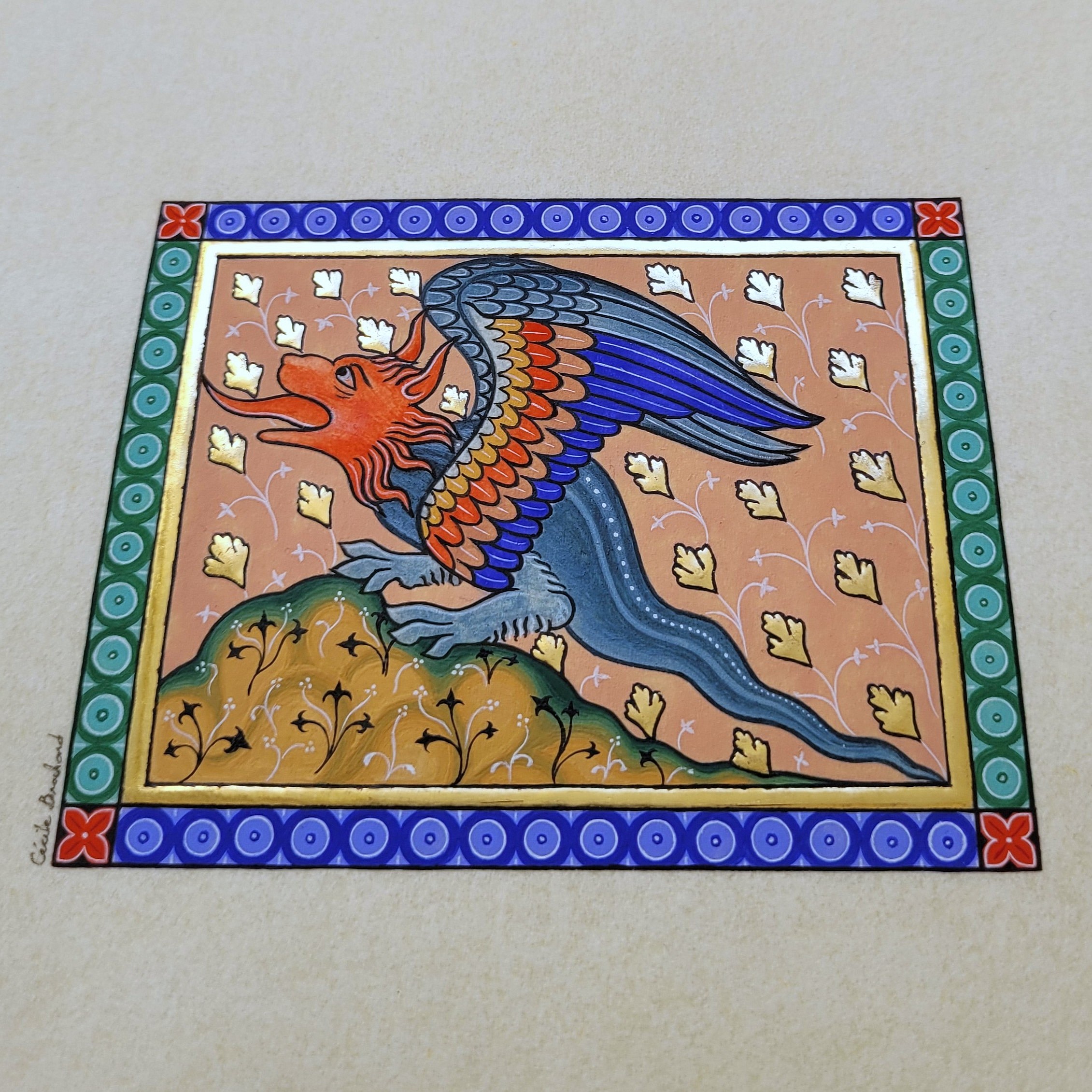 Enluminure médiévale d'un dragon coloré sur papier doré.