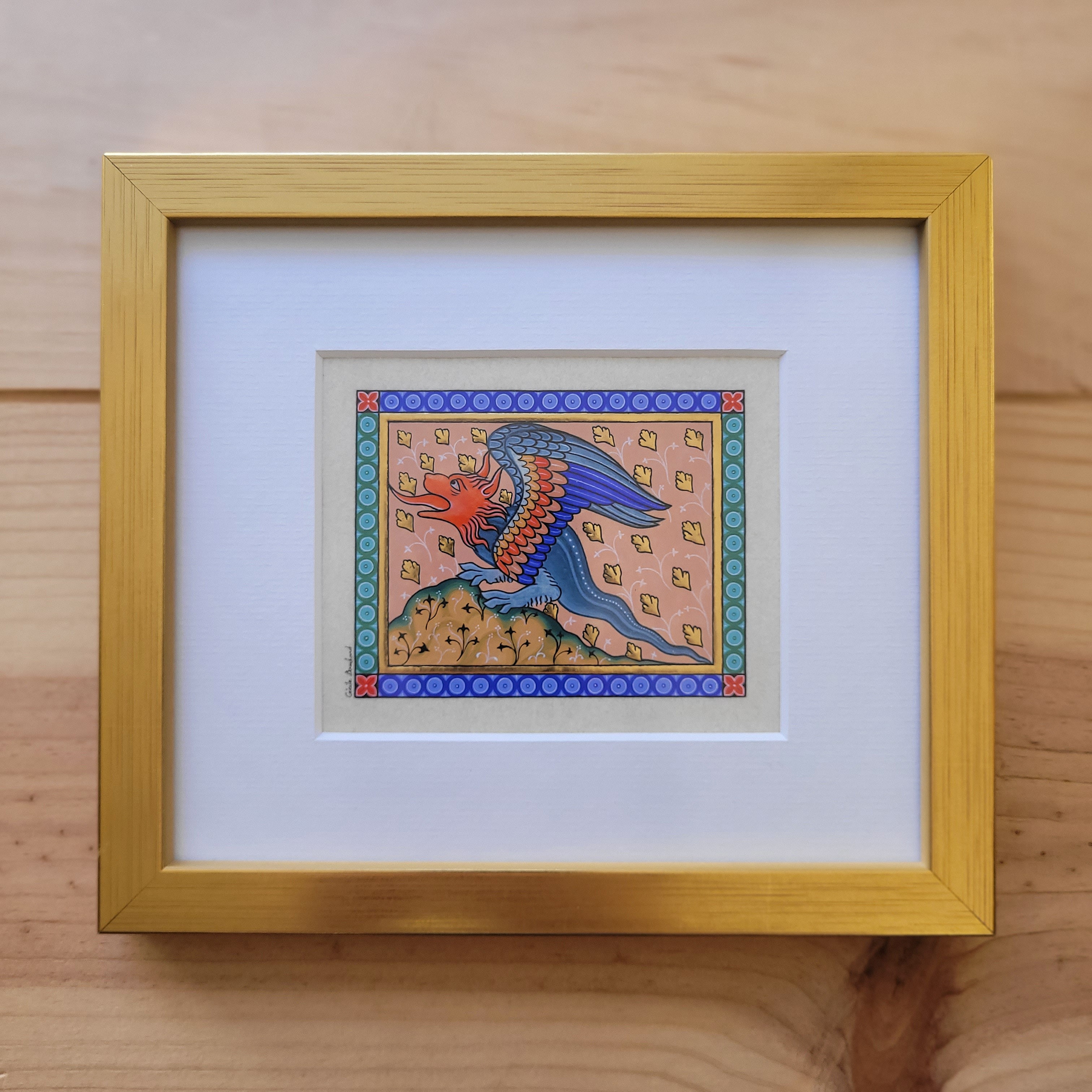 Enluminure médiévale d'un dragon sous cadre en bois doré.