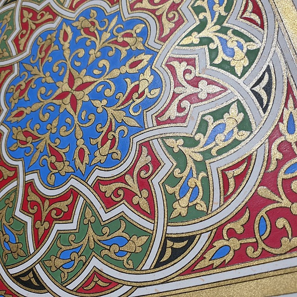 Enluminure marocaine authentique avec arabesques dorées, rouges, vertes et bleues.