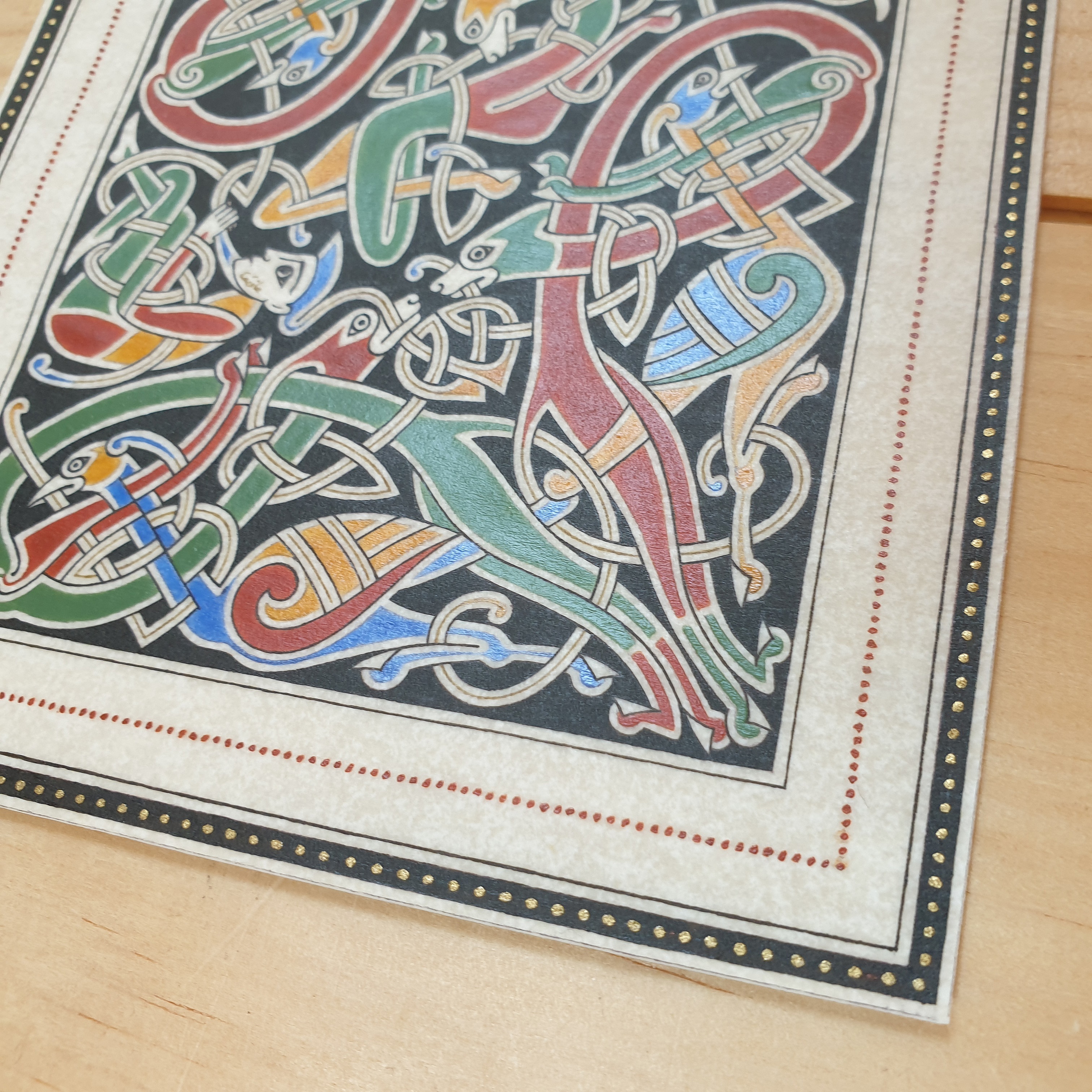 Enluminure insulaire aux entrelacs zoomorphes sur fond noir.