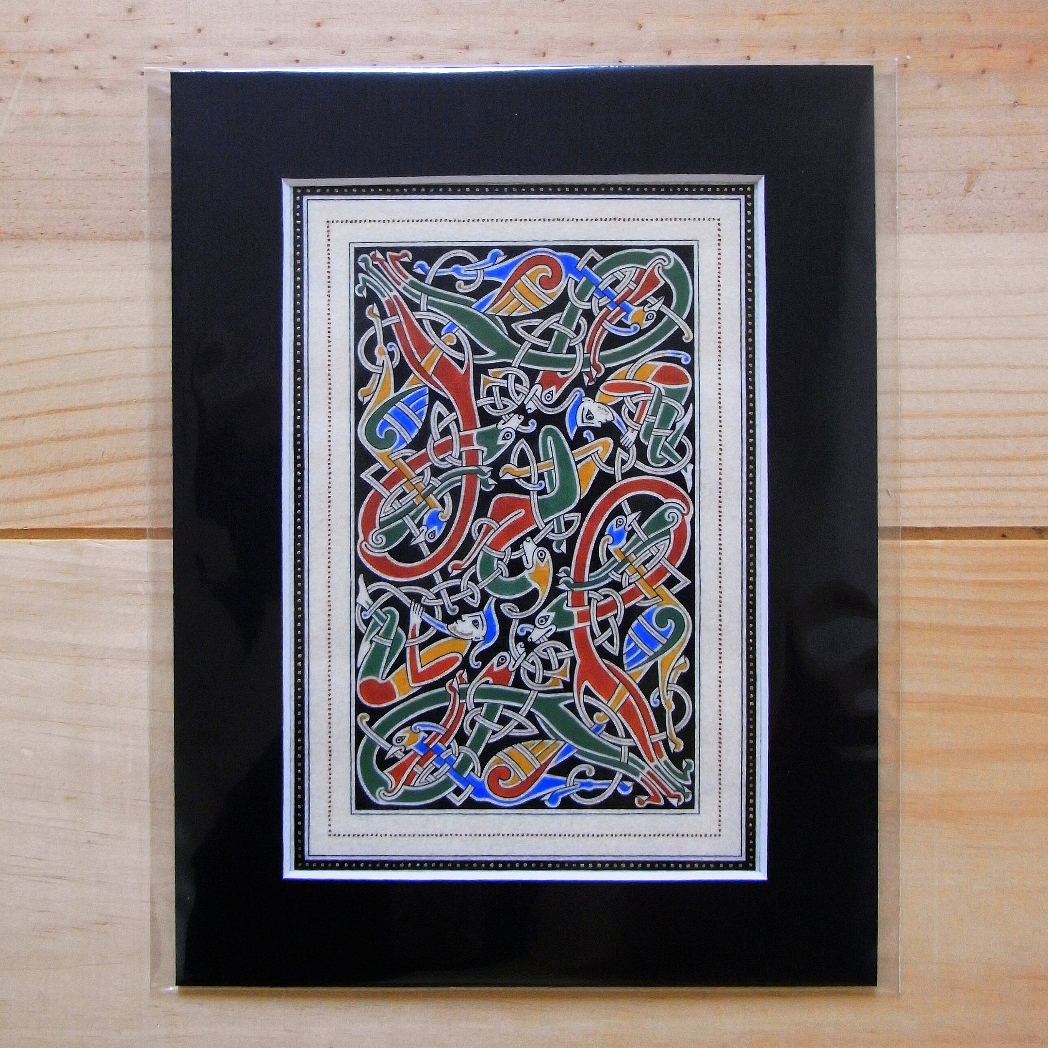 Enluminure insulaire avec entrelacs zoomorphes sur fond noir.