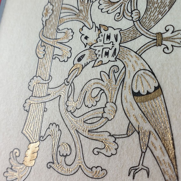 Lettre R enluminée au style roman avec oiseau doré.